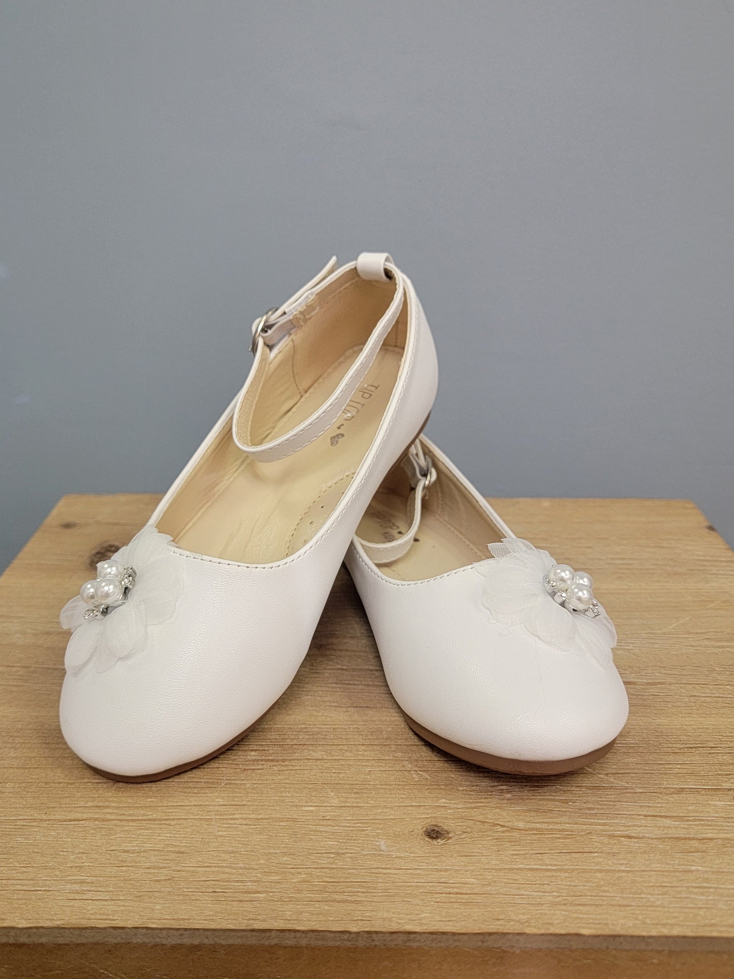 girl's white shoe with strap and flower on toe