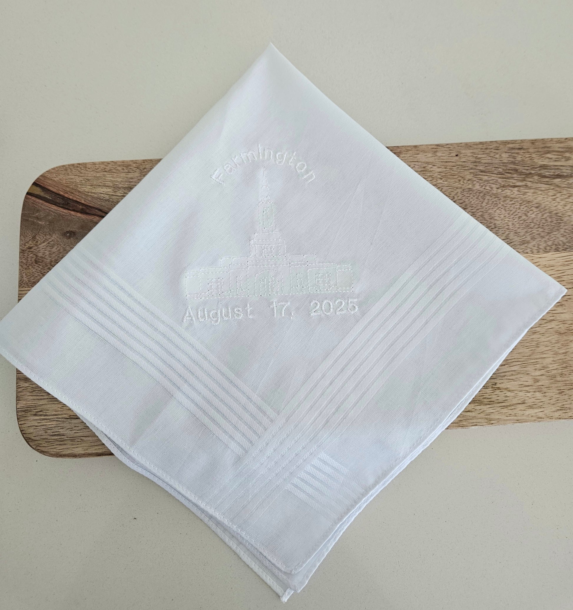 White hankie with embroidered temple and date.