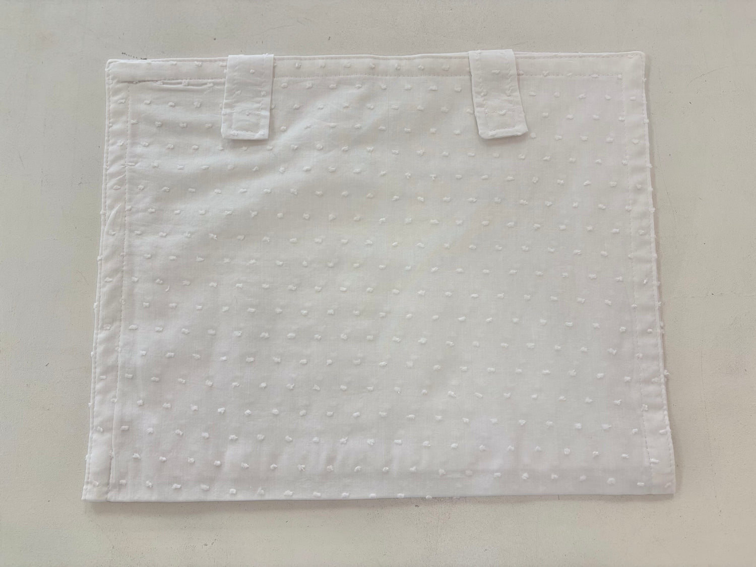 White cotton envelope with Velcro strap closure.