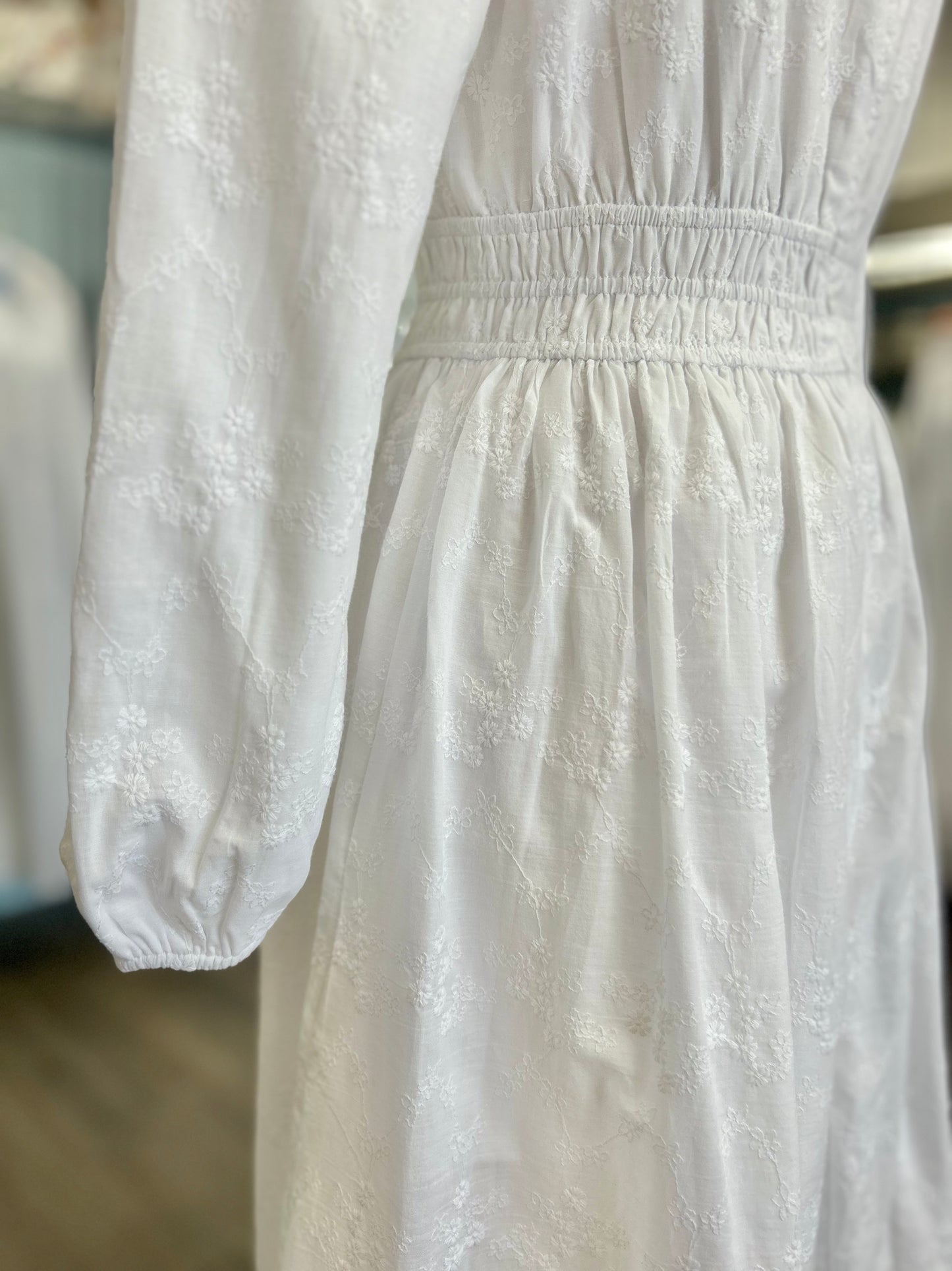 White dress with cinched waist and bishop sleeves.