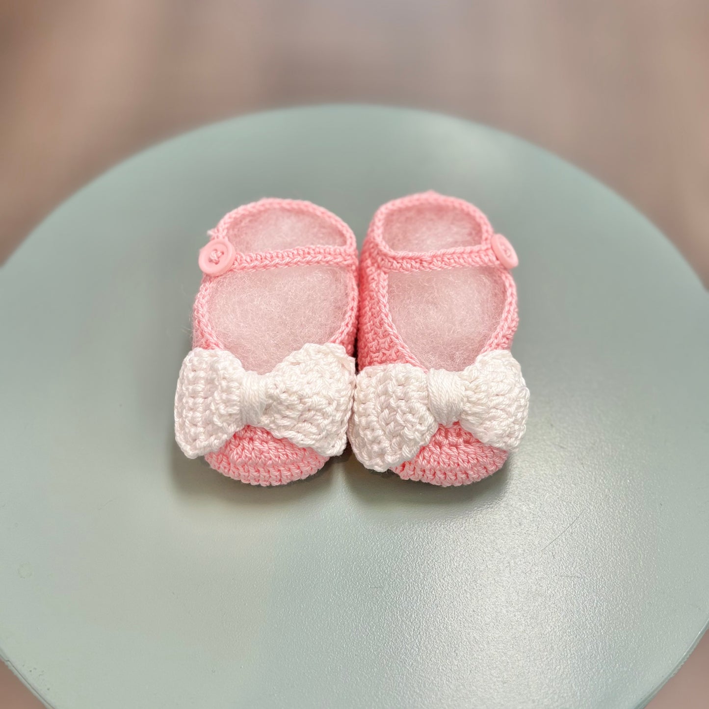 Pink crochet baby booties with white bow.