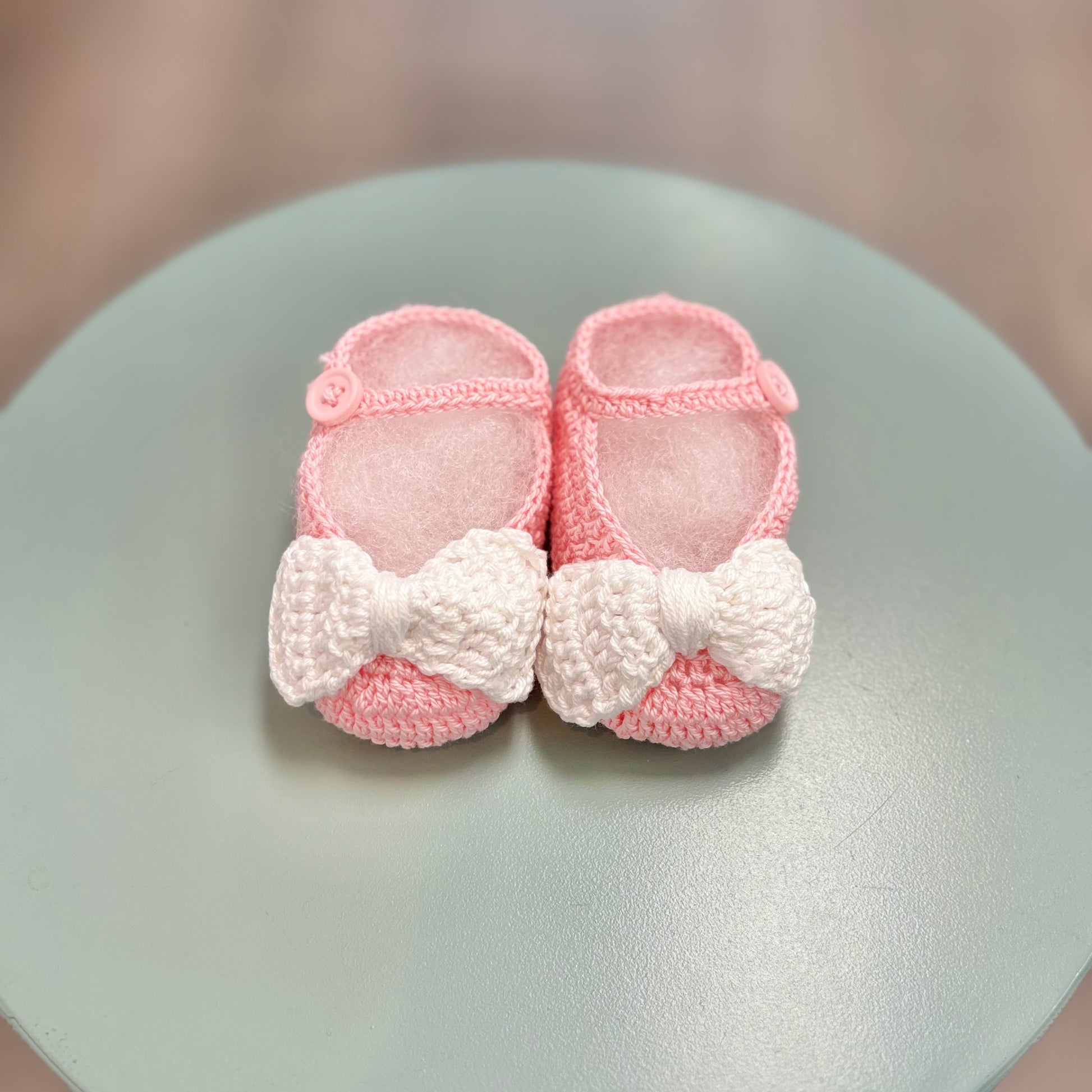 Pink crochet baby booties with white bow.