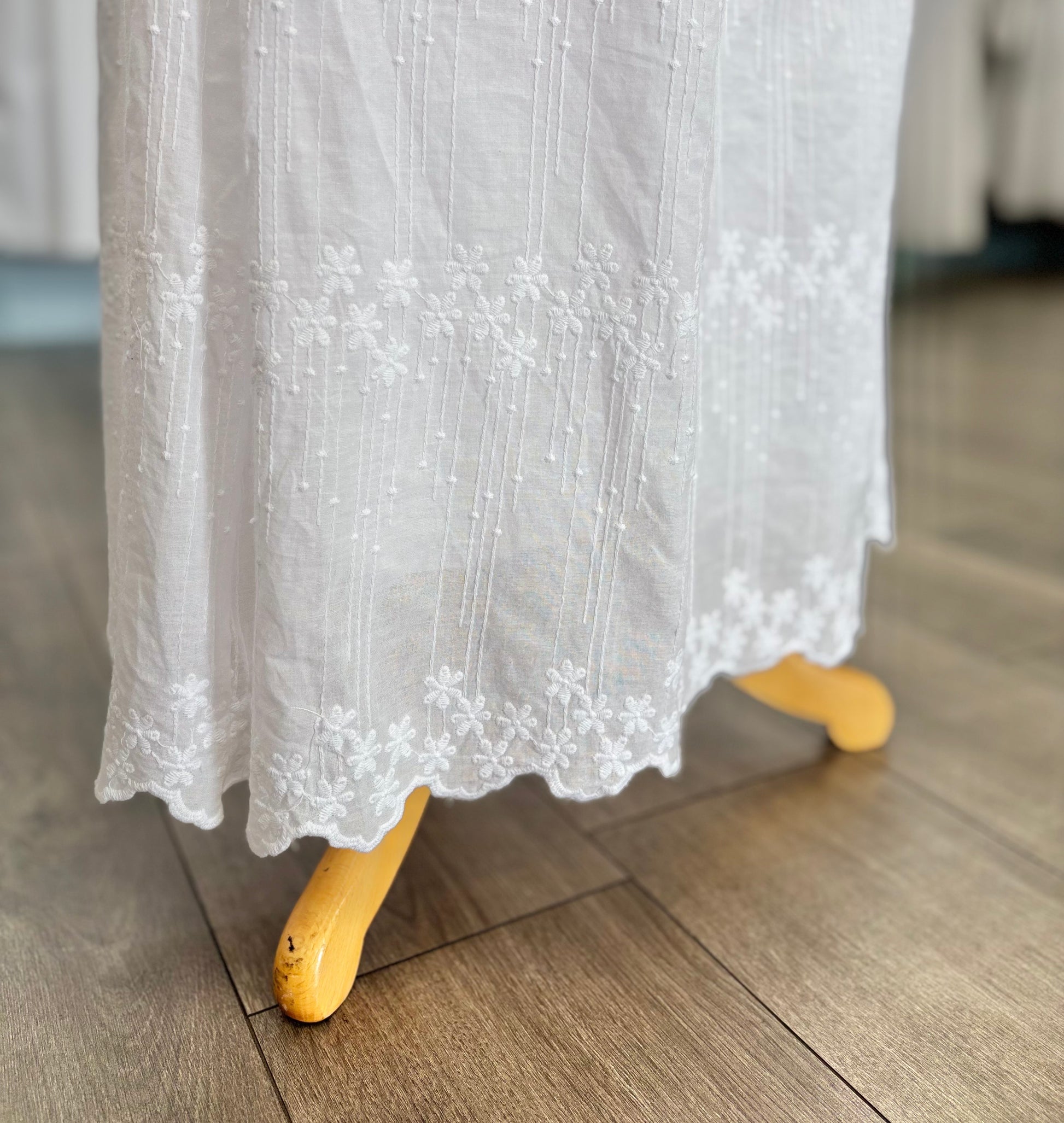 Scalloped hem of white dress. 