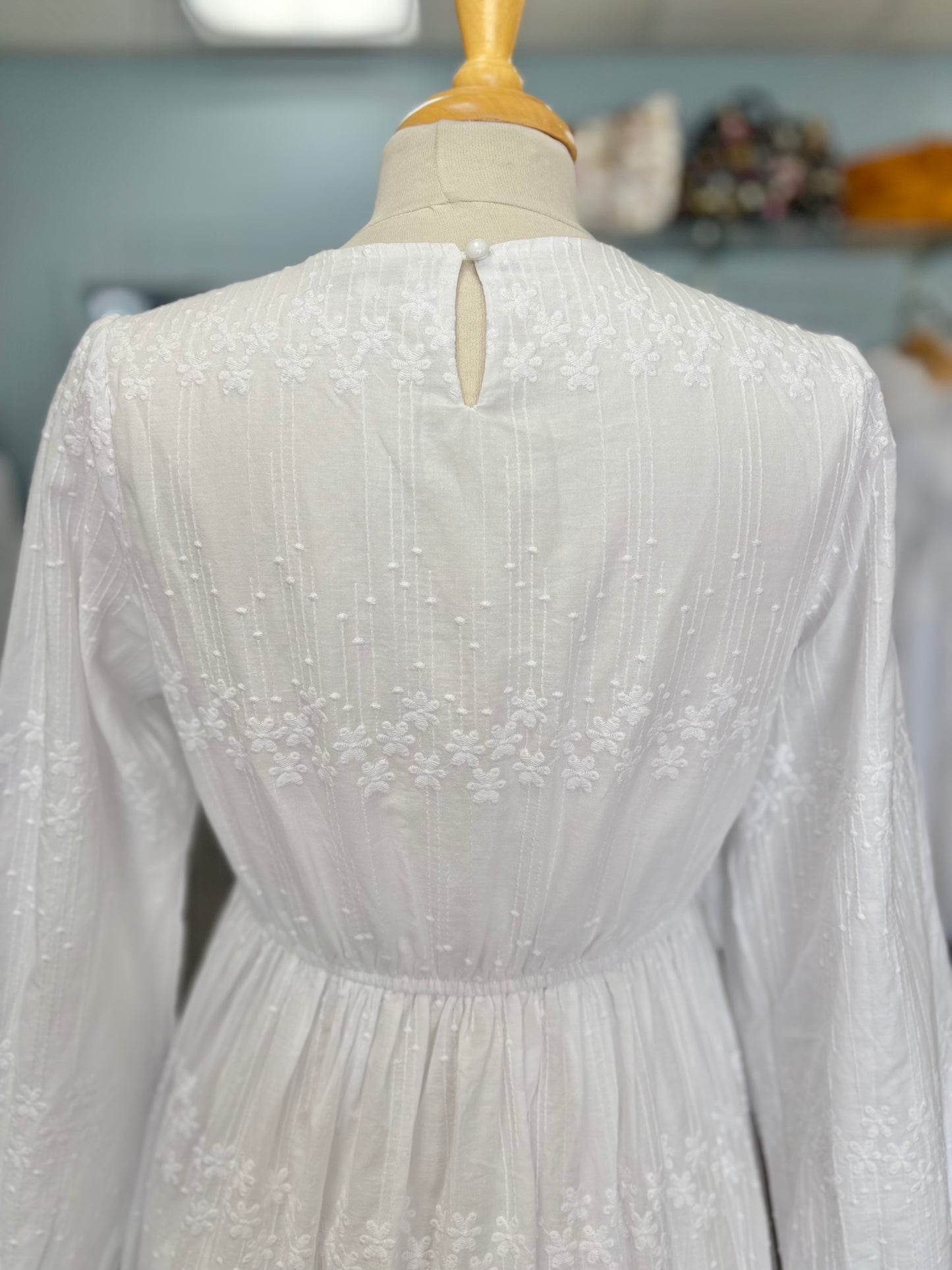 Close up of back button on long white dress. 